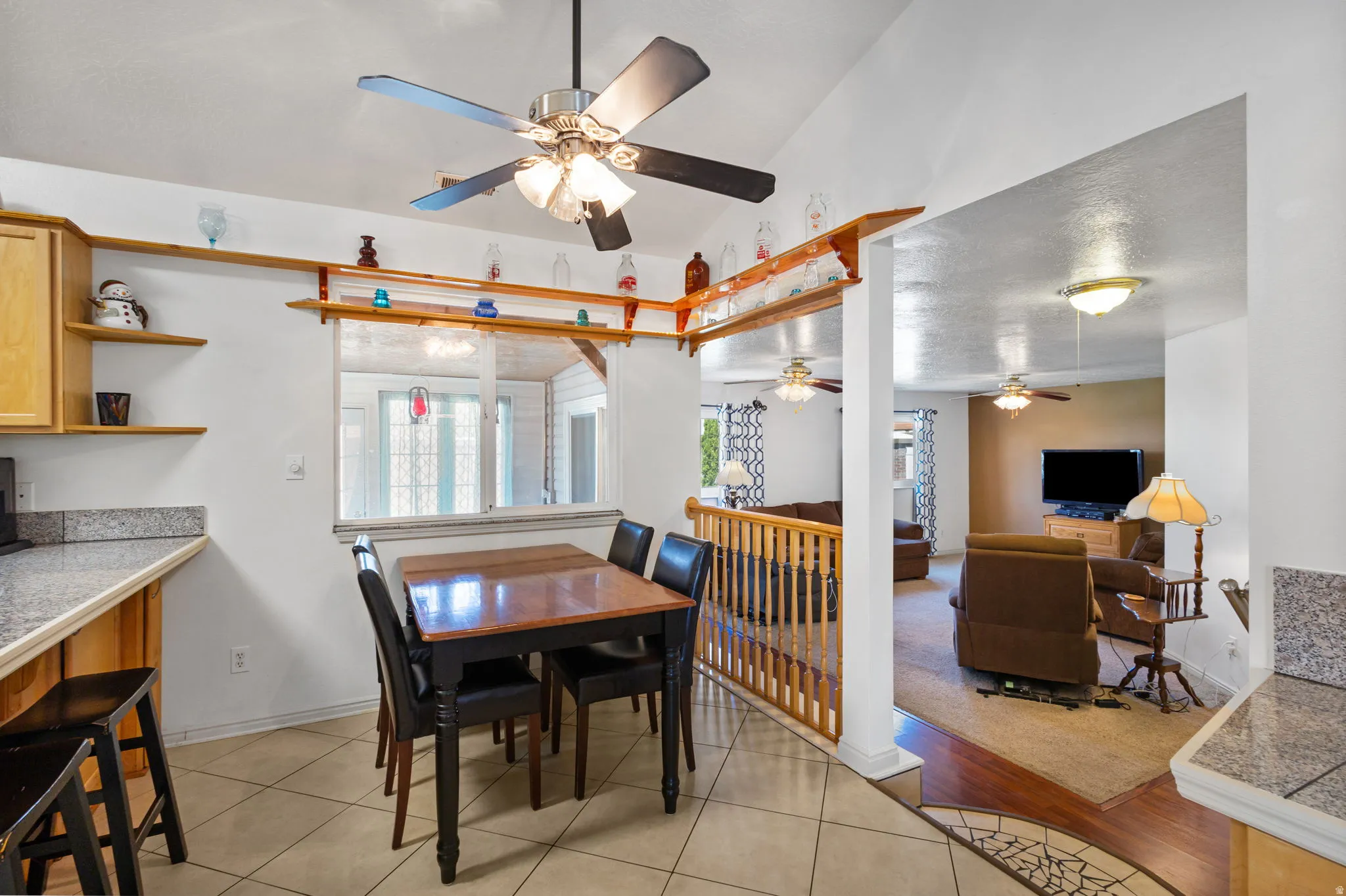 Dining space with a ceiling fan, light tile patterned floors, and vaulted ceiling