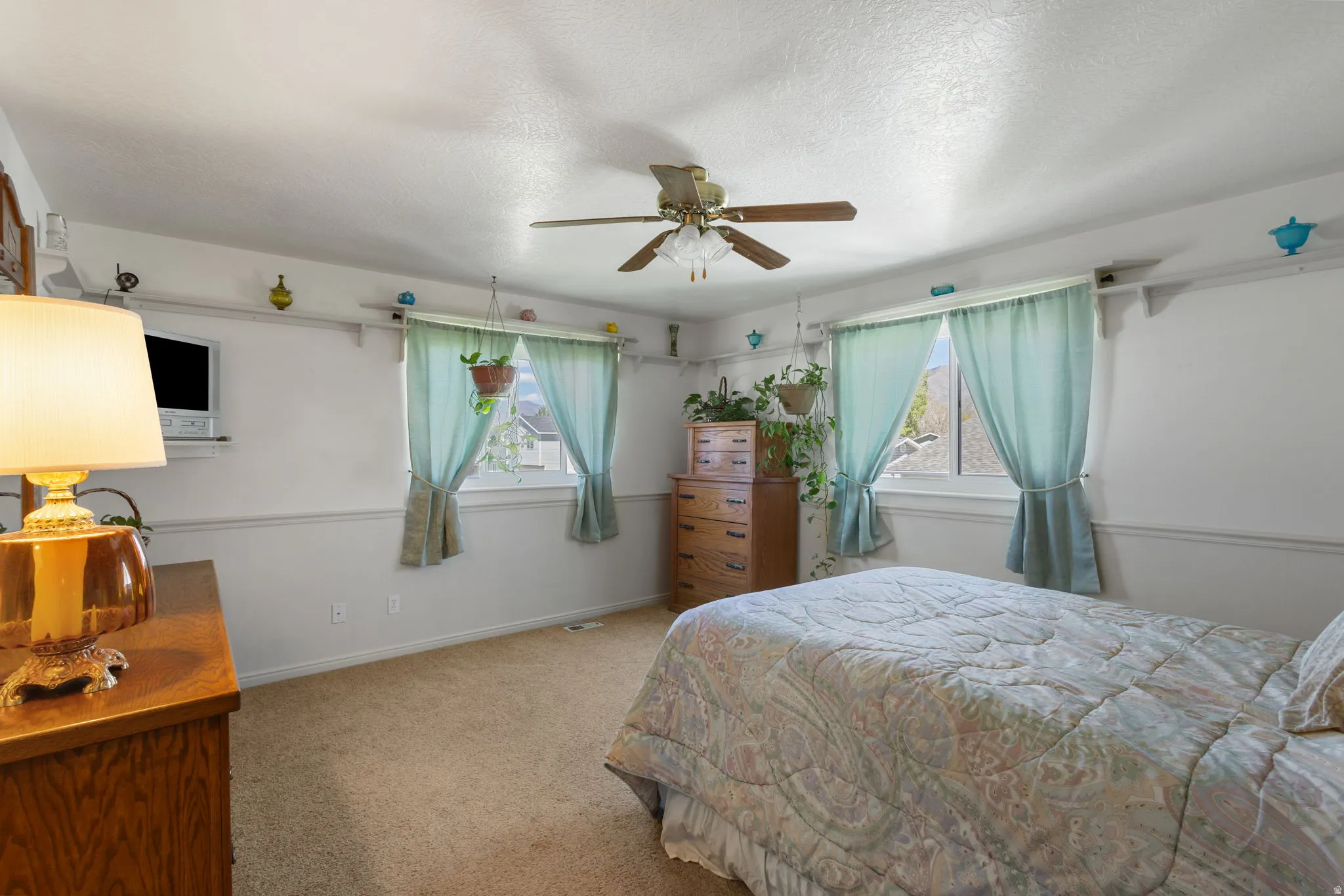 Carpeted bedroom featuring a ceiling fan and a textured ceiling