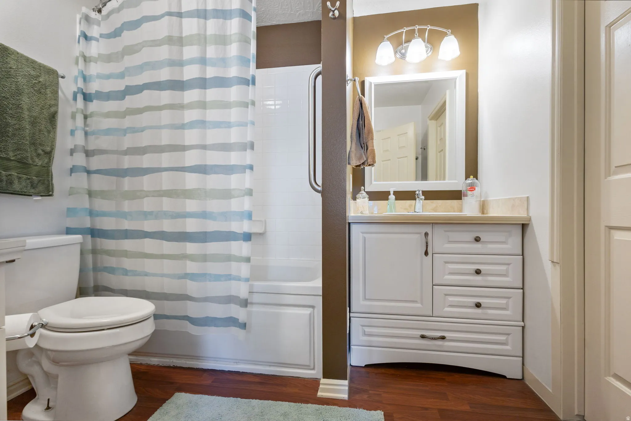Bathroom featuring vanity, dark wood-style flooring, and shower / bathtub combination with curtain