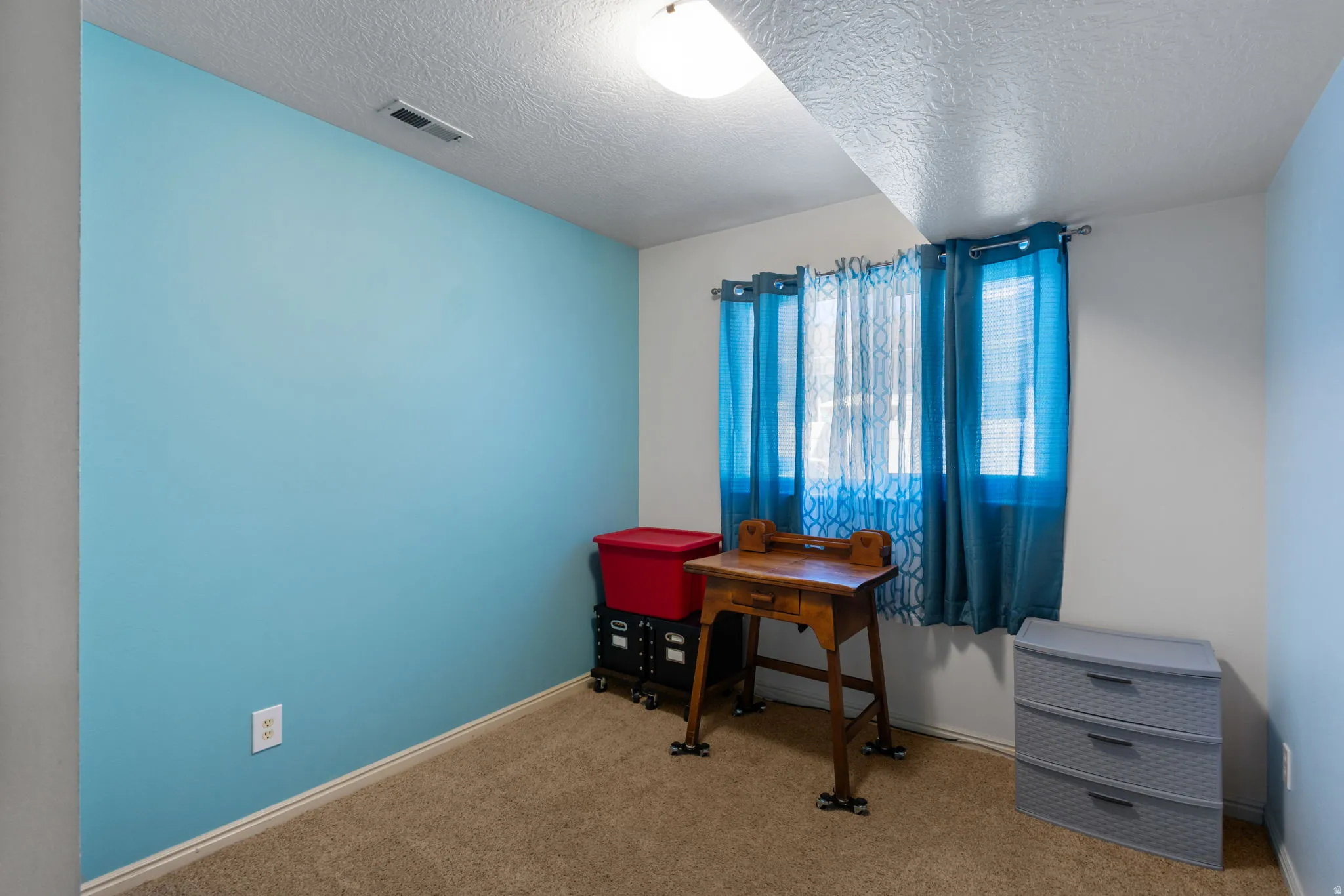 Office space with a textured ceiling and light carpet