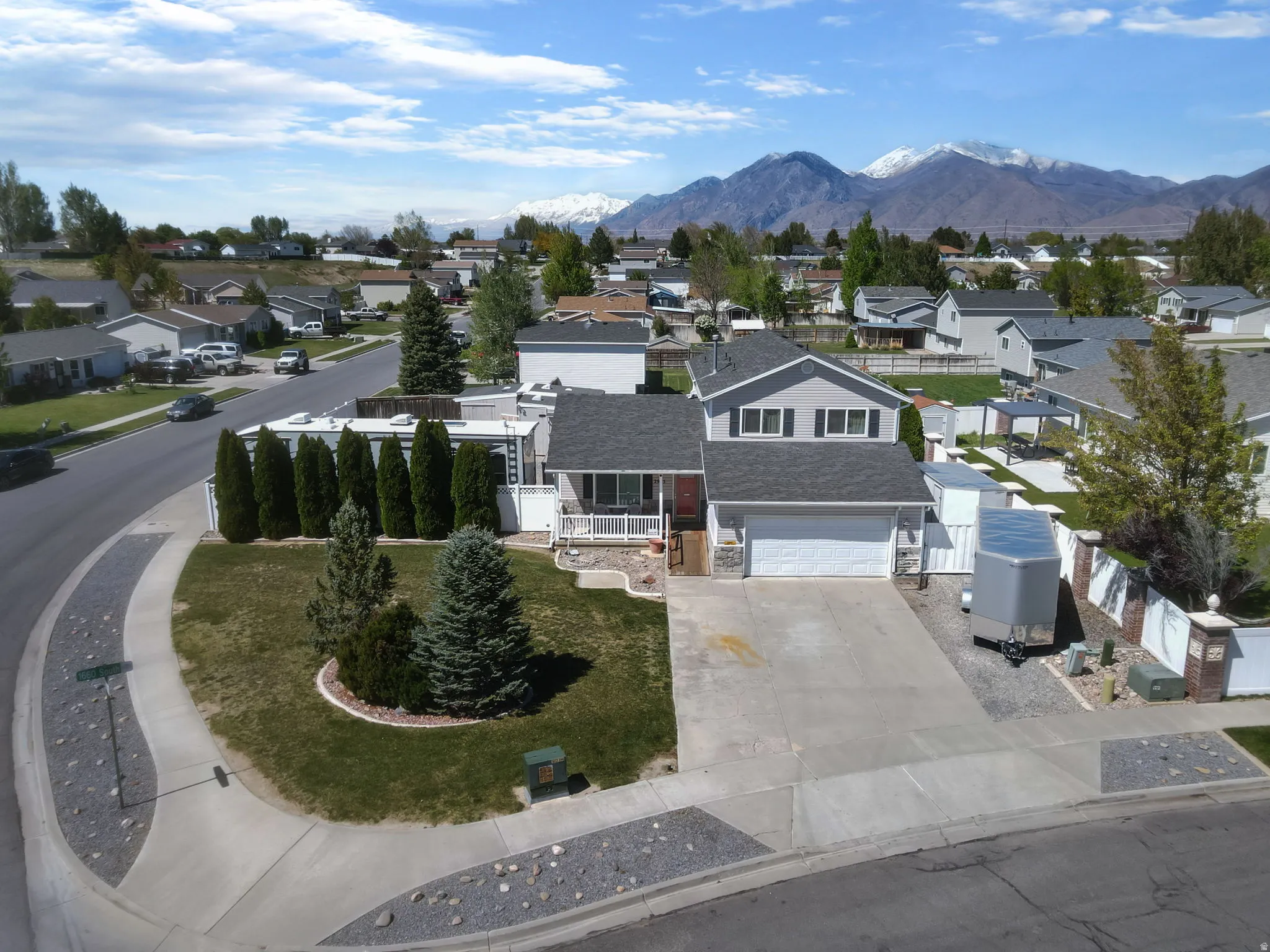 View of front of property featuring driveway, a residential view, a mountain view, a garage, and a balcony