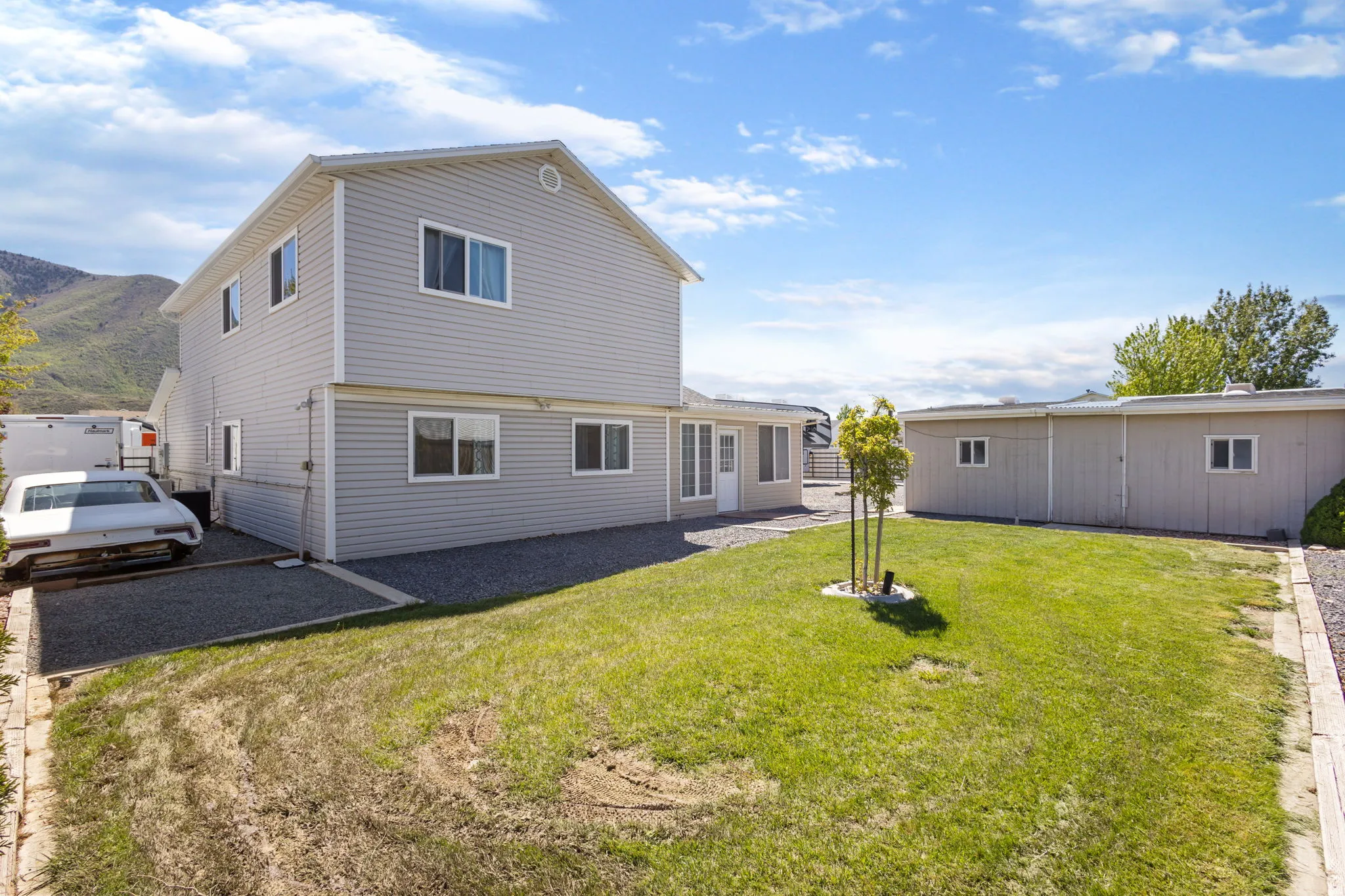 Back of property featuring a patio area, a yard, and a mountain view