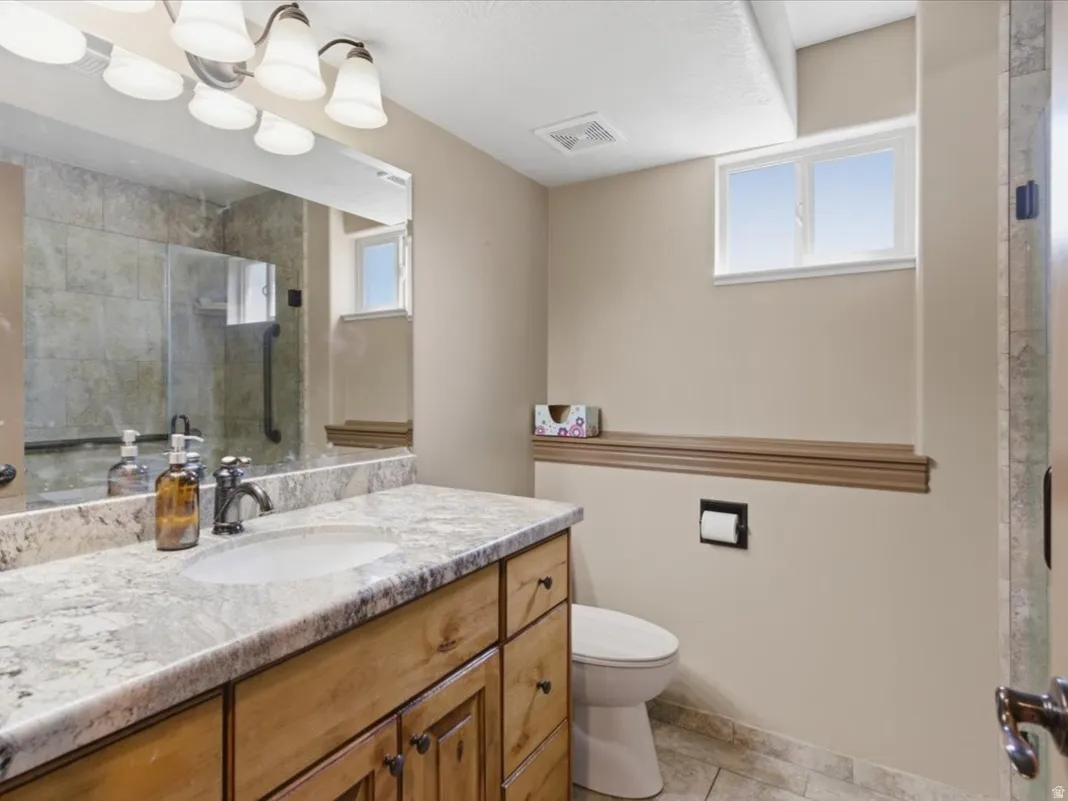 Bathroom featuring a light-toned vanity with an integrated sink and a speckled countertop