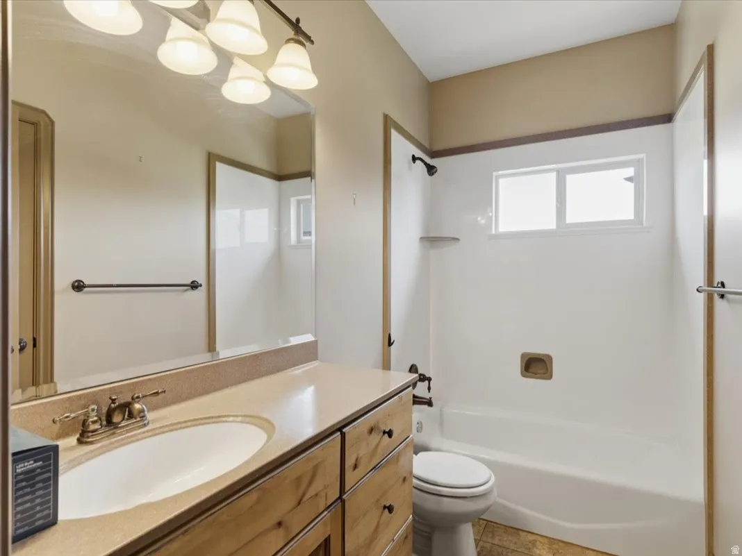 Bathroom featuring a light-toned vanity with an integrated sink, a rectangular mirror, and a wall-mounted light fixture