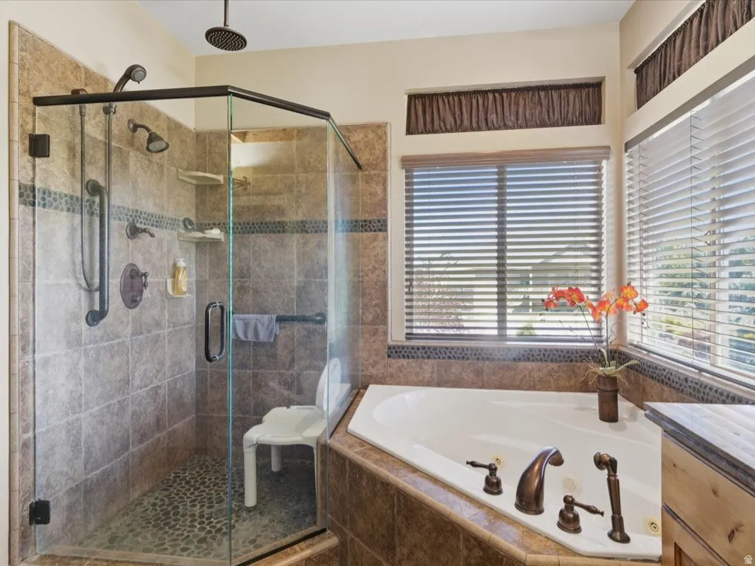 Tiled walk-in shower with a pebble floor, multiple showerheads, and bronze fixtures