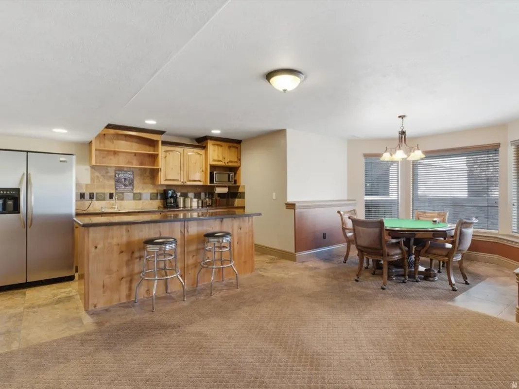 Entertainment area featuring a wood-finish bar with a dark countertop, stainless steel refrigerator, and wood-finish cabinetry