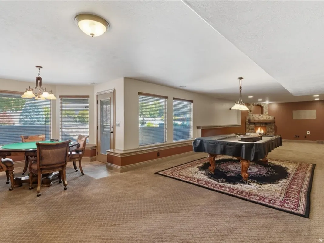 Spacious lower-level entertainment area featuring a stone fireplace, recessed lighting, and multiple windows