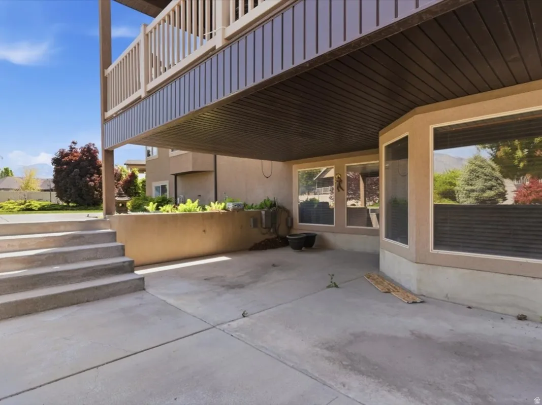 Concrete patio with multi-level steps, framed by a stucco exterior and large window array