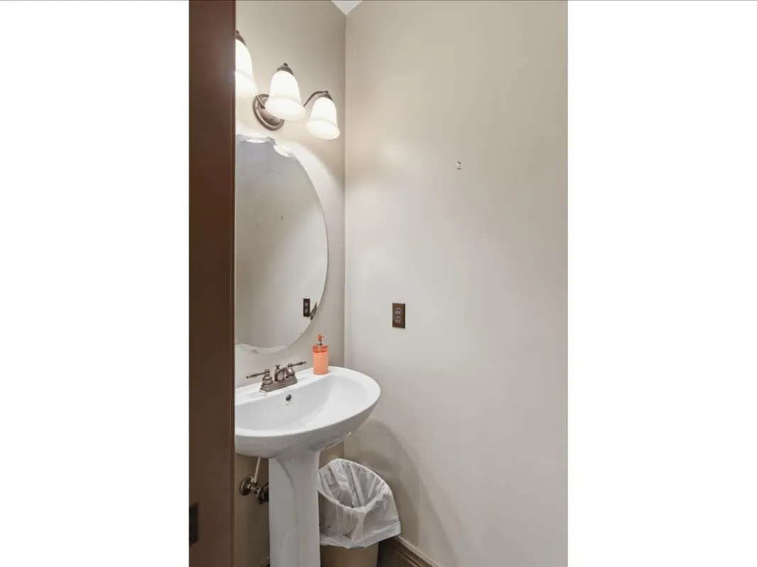 Pedestal sink with chrome-finish faucet and oval mirror