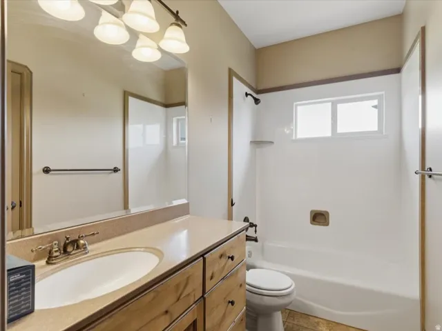 Bathroom featuring a light-toned vanity with an integrated sink, a rectangular mirror, and a wall-mounted light fixture