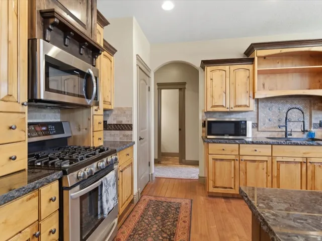 Kitchen featuring wood cabinetry, dark countertops, and stainless steel appliances including a gas range and built-in microwave