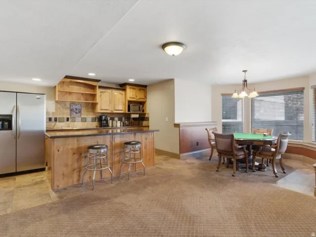 Entertainment area featuring a wood-finish bar with a dark countertop, stainless steel refrigerator, and wood-finish cabinetry