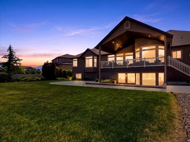 Rear exterior with a spacious lawn, covered patio, and ground-level patio access