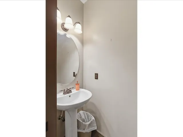 Pedestal sink with chrome-finish faucet and oval mirror