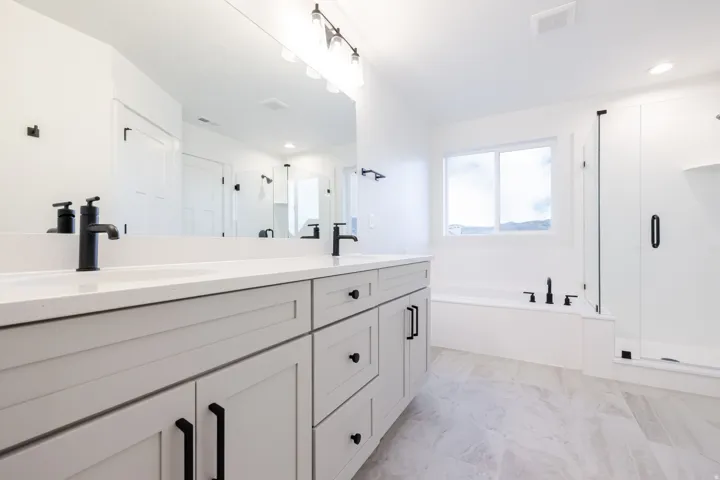 Dual vanity with quartz countertops, matte black fixtures, and light-toned cabinetry