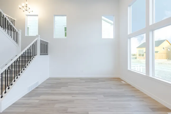 Expansive windows providing abundant natural light, wood-finish flooring, and a modern chandelier
