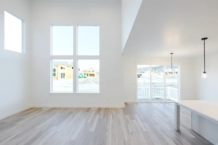 Vaulted ceiling, large multi-pane windows, wood-finish flooring, sliding glass door, and a kitchen island with pendant lighting