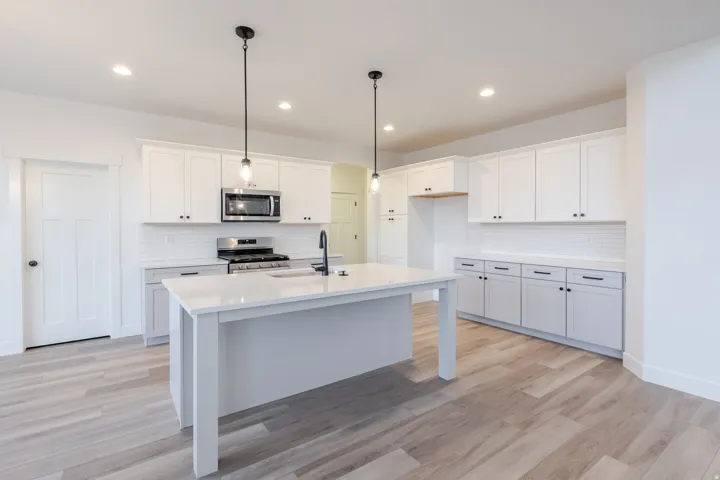 Kitchen featuring white cabinetry, a central island with countertop, stainless steel appliances, and wood-finish flooring