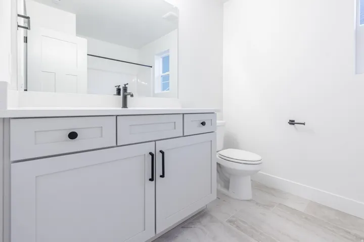 Light-toned wood-finish flooring complements the vanity with shaker-style cabinetry and a white countertop