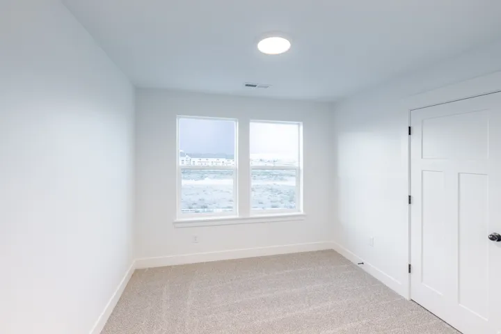 Neutral carpet flooring, white walls, two pane windows, recessed lighting, and a white interior door