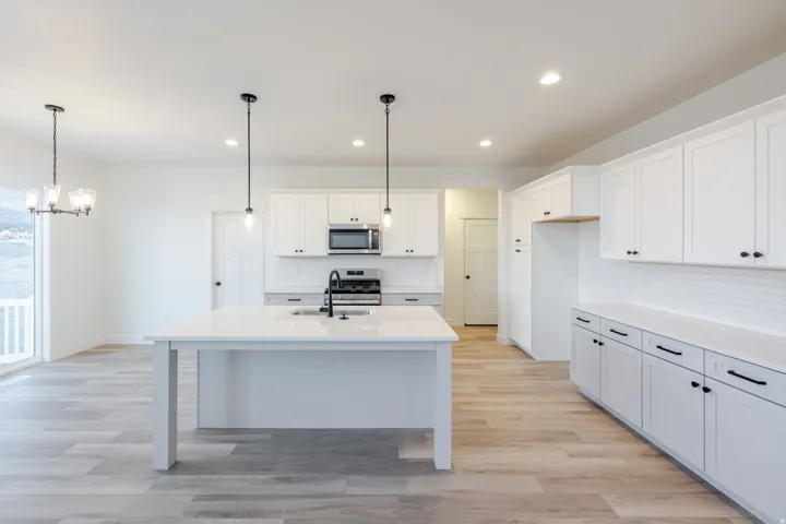 Modern kitchen featuring a large island, white shaker cabinetry, stainless steel appliances, and wood-finish flooring