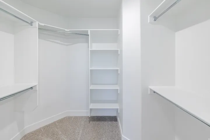 White built-in shelving, hanging rods, and light-colored carpet