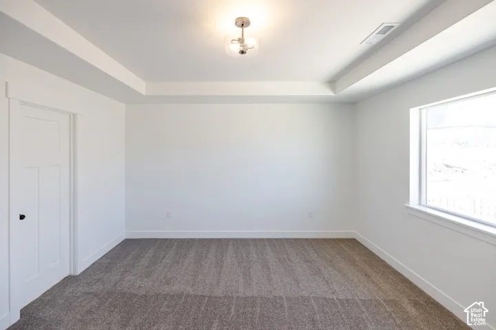 Recessed ceiling details, neutral carpet flooring, contemporary light fixture, white trim, and a clear window