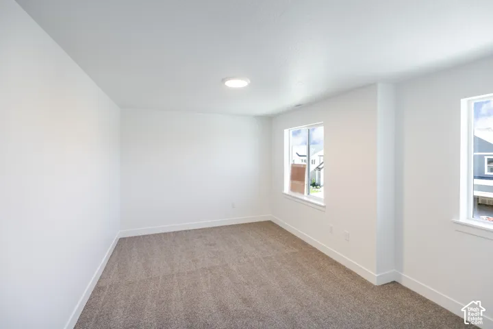 Recessed ceiling lighting, two windows with white trim, white walls, and gray carpet