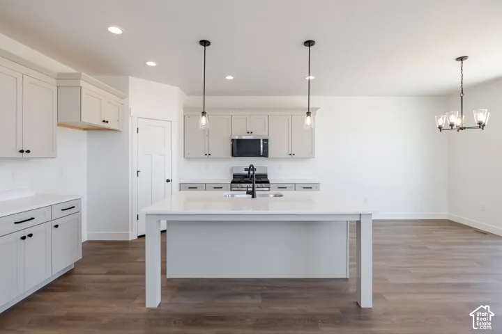 Kitchen featuring light-toned cabinetry, a spacious island with a countertop, wood-finish flooring, recessed lighting, and modern pendant fixtures