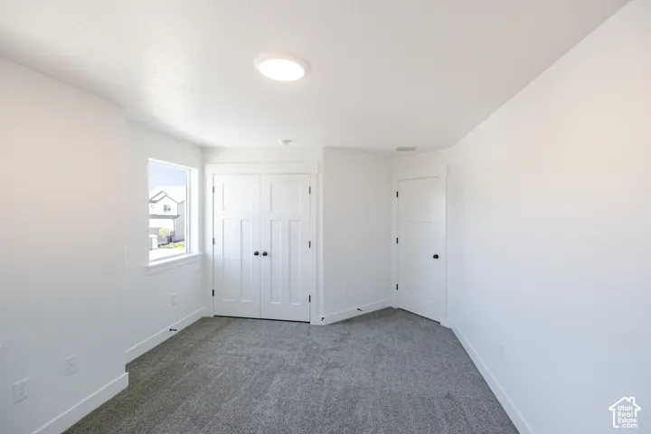 Neutral-toned wall-to-wall carpeting, white walls, and a window with white trim