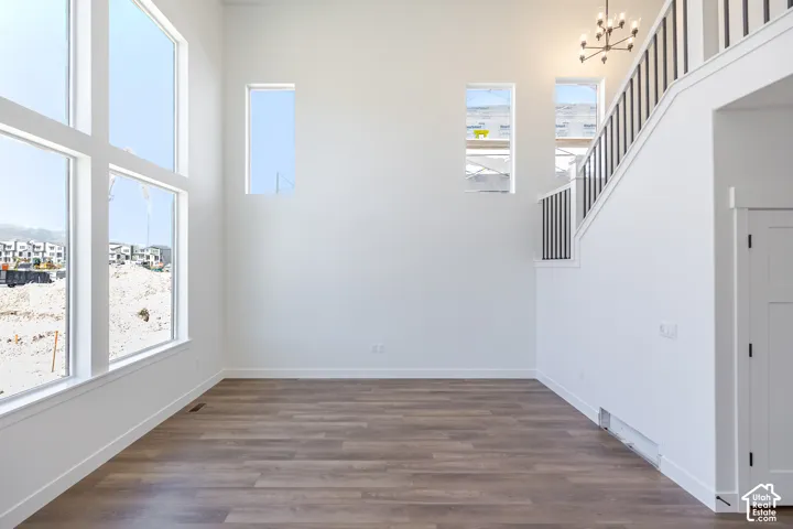 Expansive wall of multi-pane windows, wood-finish flooring, white walls, modern chandelier, and a staircase with black spindles