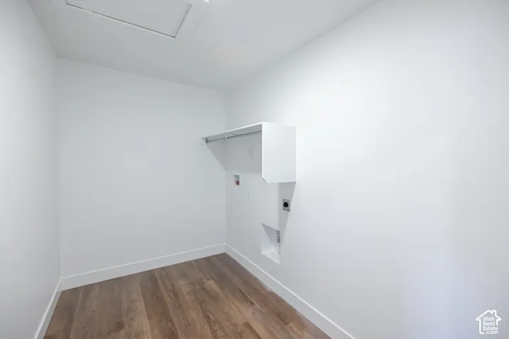 Bright interior with wood-finish flooring, white walls, built-in shelving, and utility connections