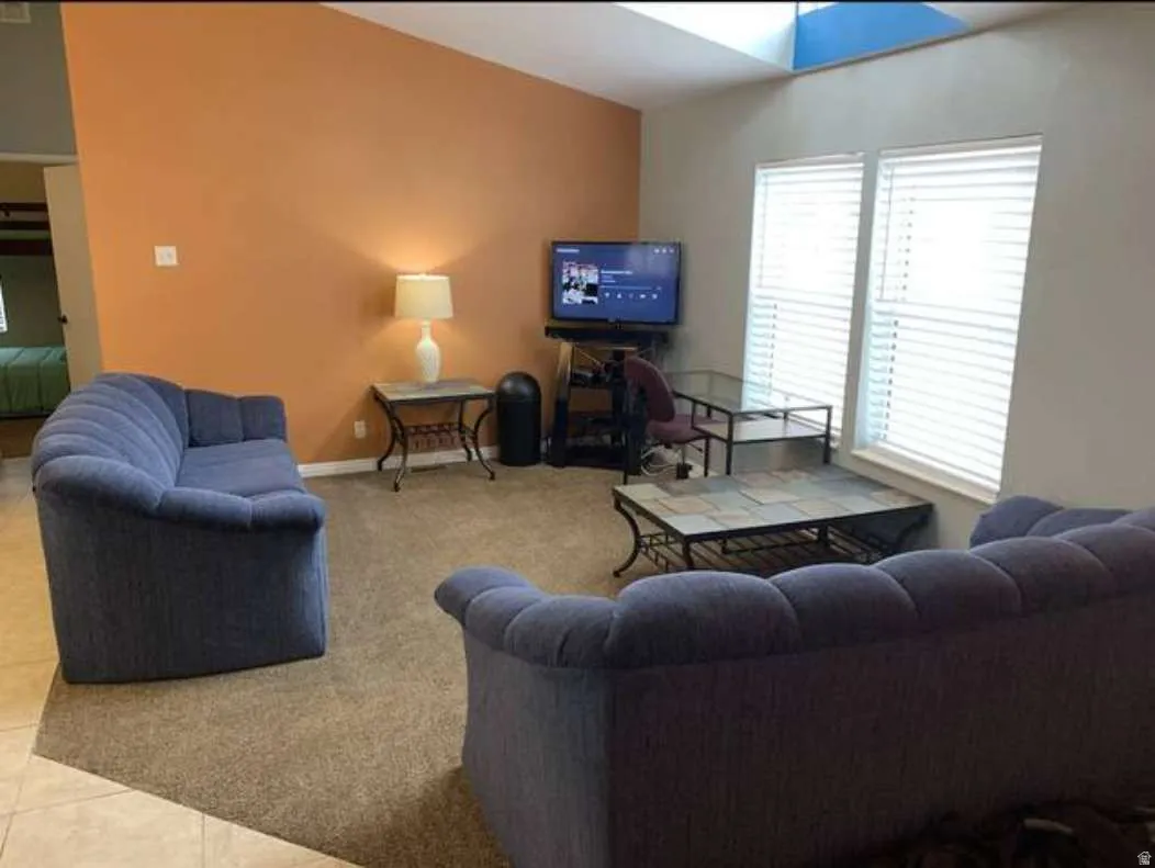 Living area with light tile patterned floors and light carpet