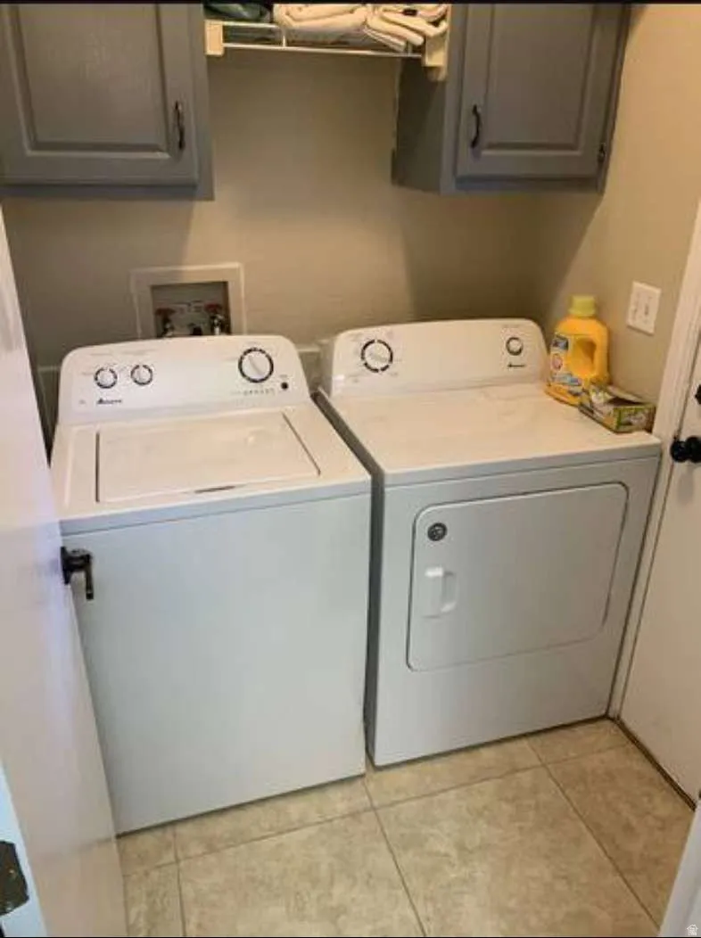 Laundry area featuring cabinet space, washer and clothes dryer, and light tile patterned floors