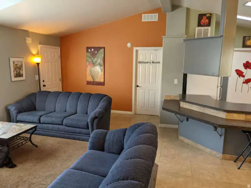 Living room with vaulted ceiling and light tile patterned flooring