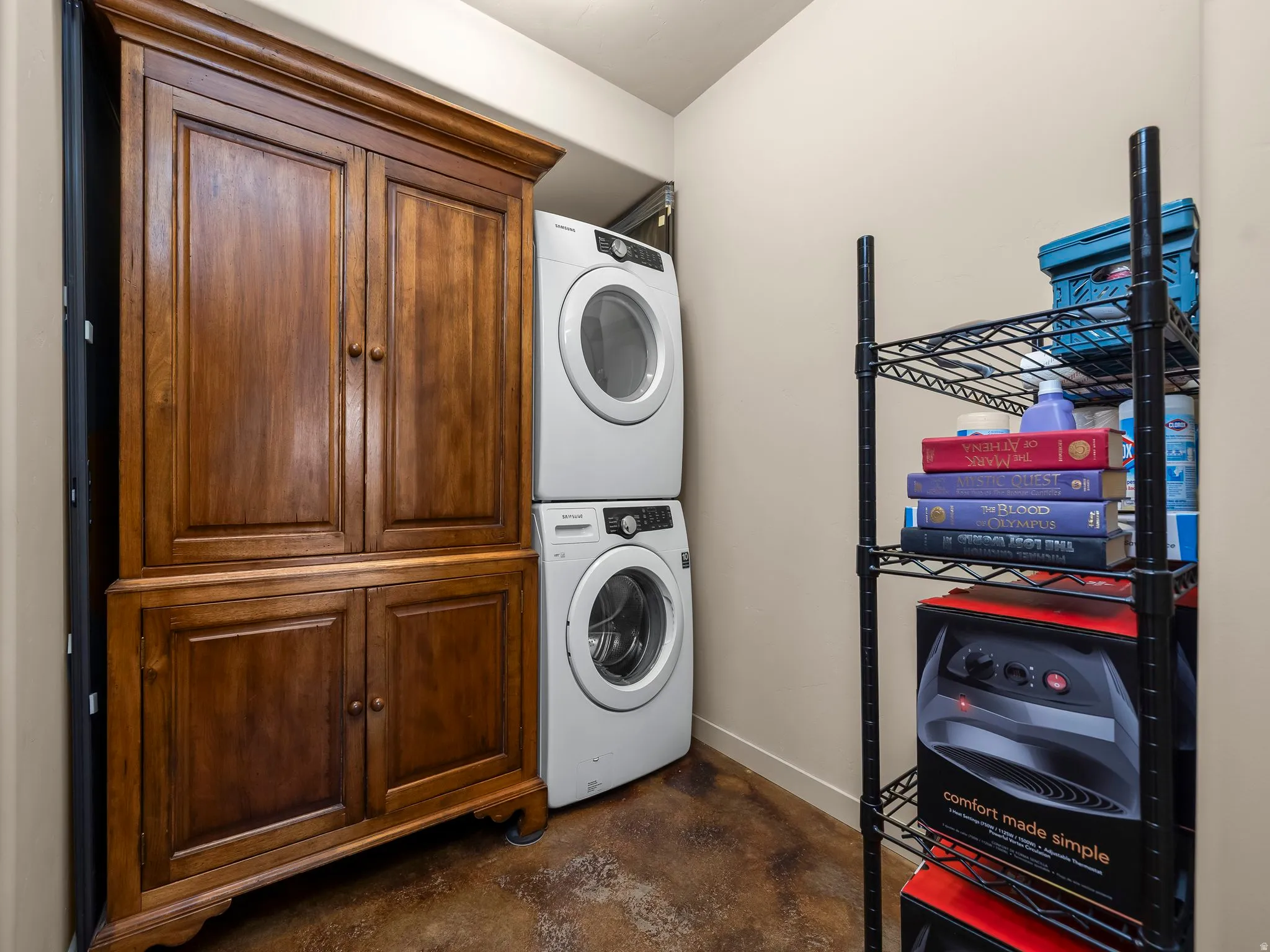 Laundry room with concrete flooring, stacked washer / dryer, and cabinet space