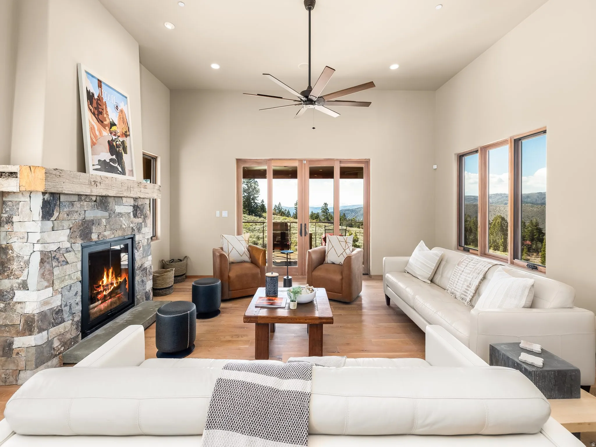 Living area featuring wood finished floors, a stone fireplace, recessed lighting, a high ceiling, and a ceiling fan