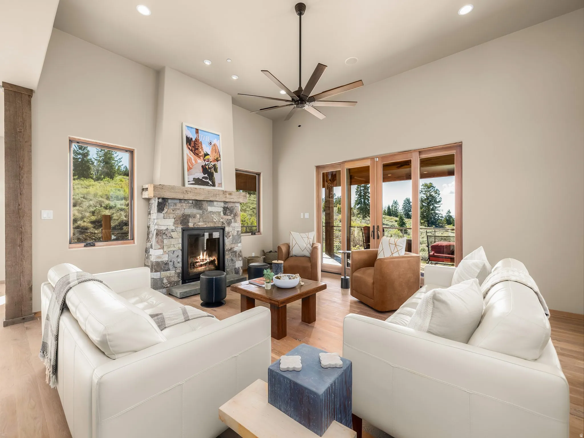 Living area featuring light wood-style flooring, a high ceiling, a fireplace, a ceiling fan, and recessed lighting