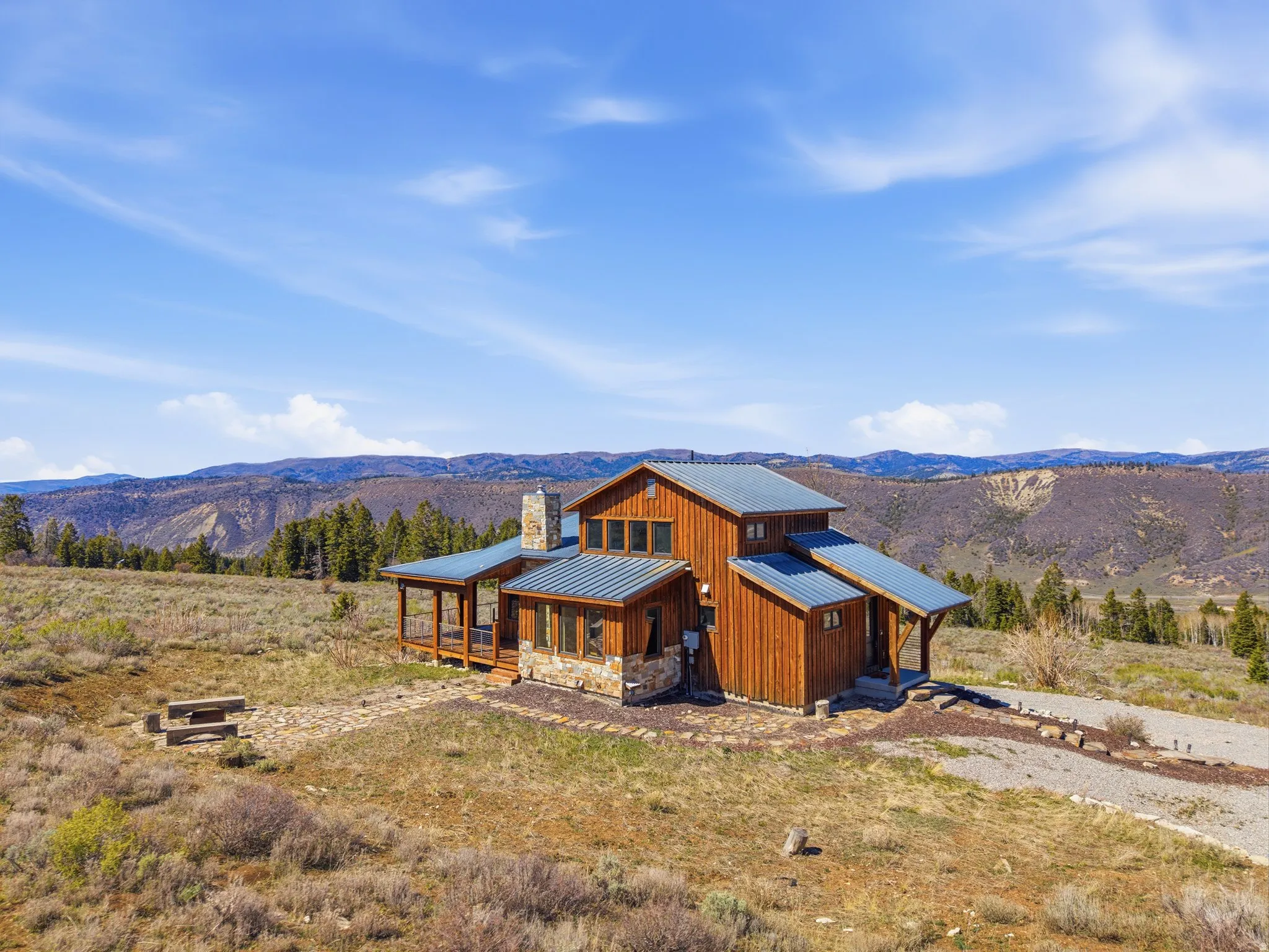 Contemporary house with a mountain view, a porch, board and batten siding, a standing seam roof, and a chimney