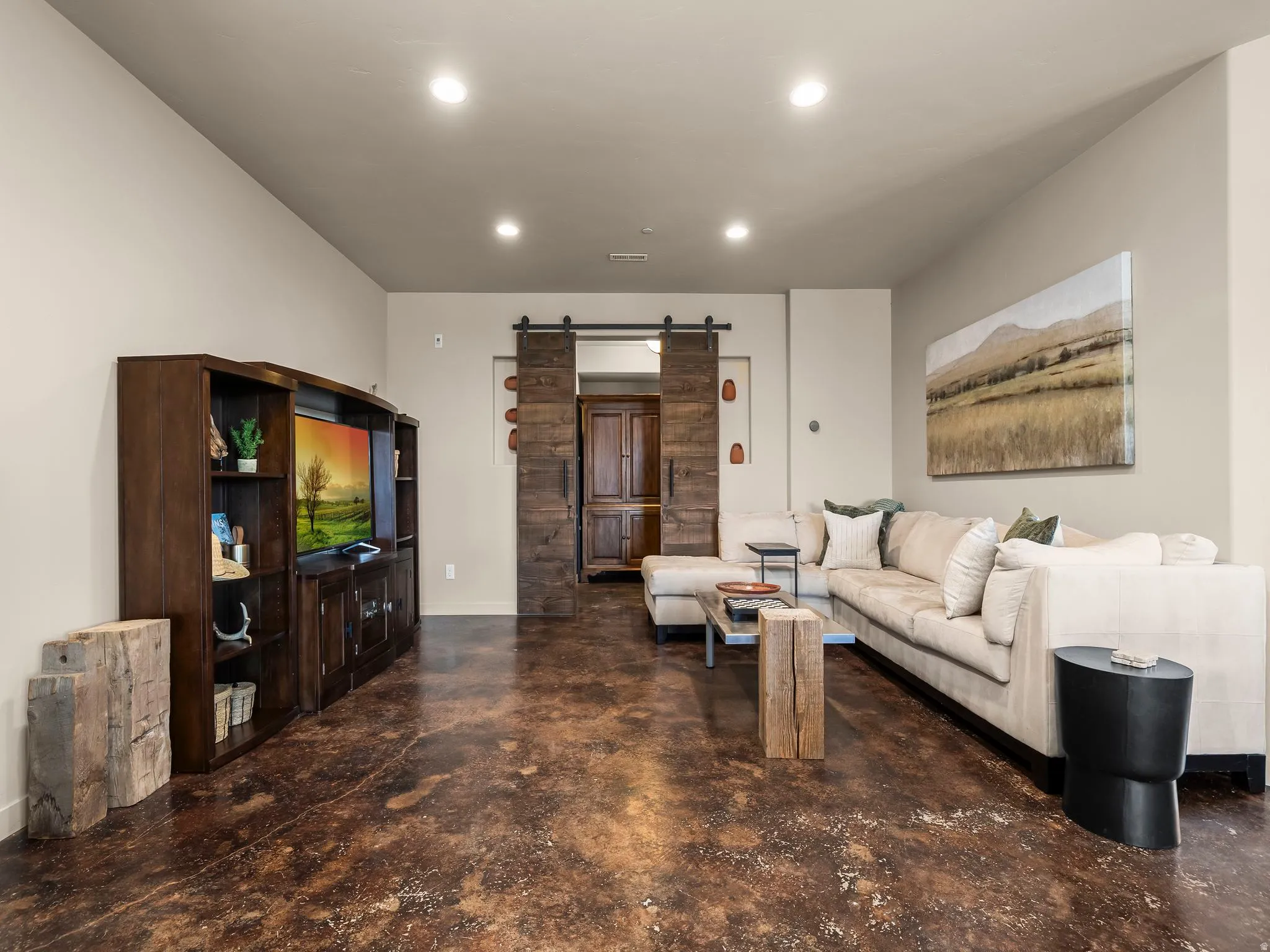 Living area featuring a barn door, finished concrete flooring, and recessed lighting