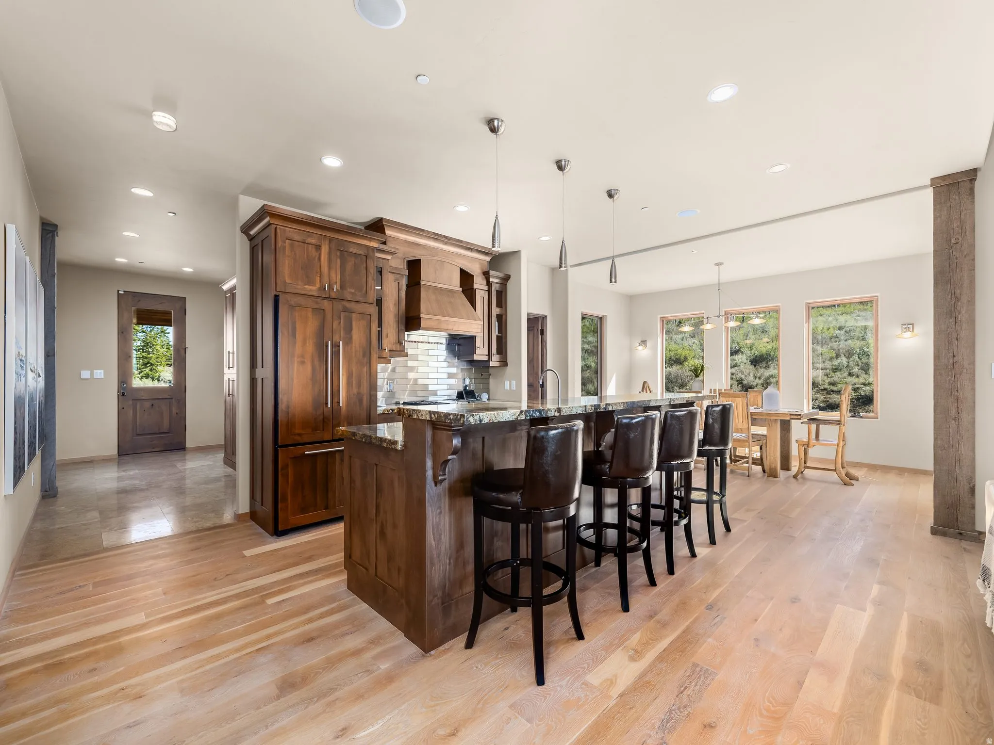 Kitchen featuring a kitchen breakfast bar, dark stone counters, a large island, pendant lighting, and light wood-style floors