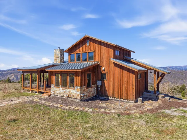 Rear view of property with a mountain view, a standing seam roof, board and batten siding, and a chimney