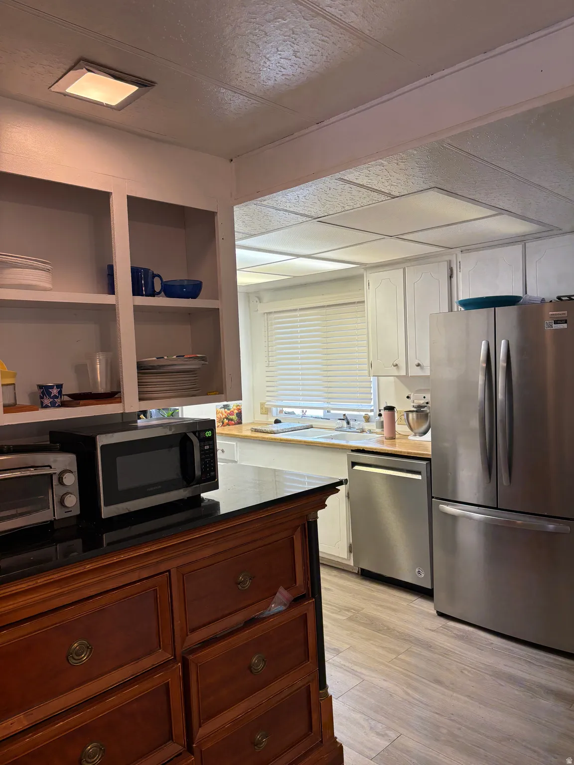 Two tone kitchen featuring stainless steel appliances, light wood-style flooring, and dual tone cabinets
