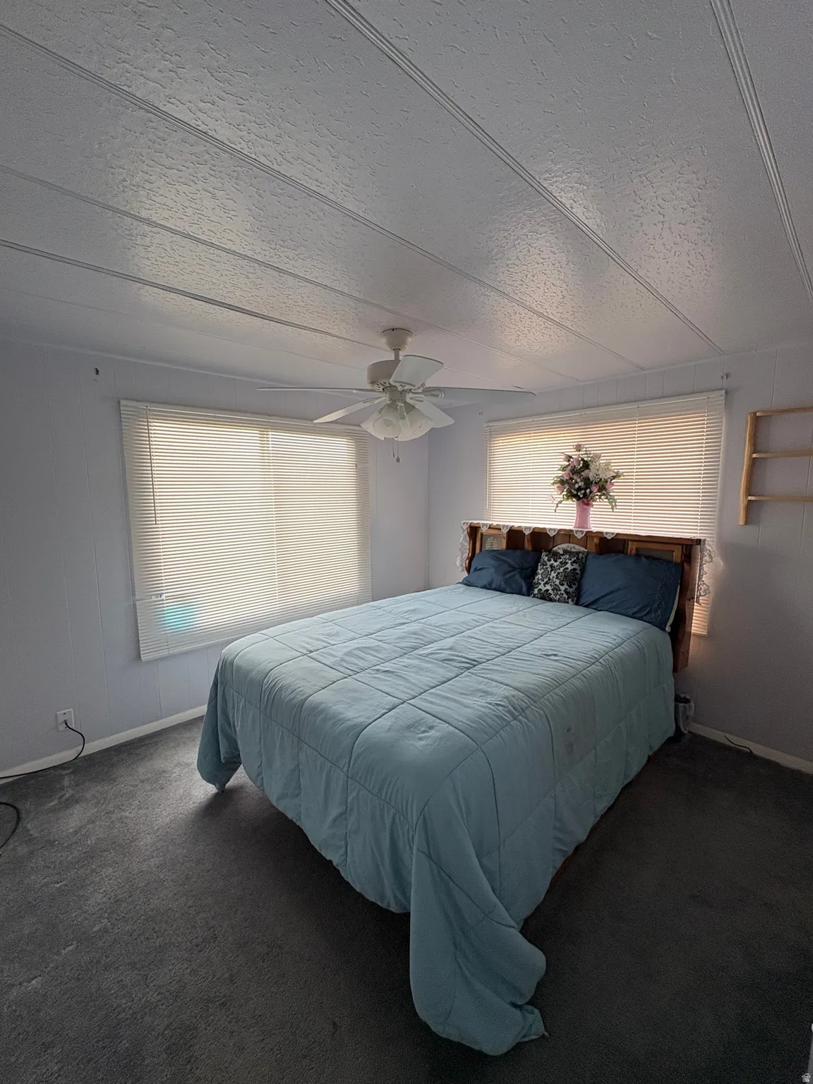 Bedroom featuring a ceiling fan, dark carpet, and a textured ceiling
