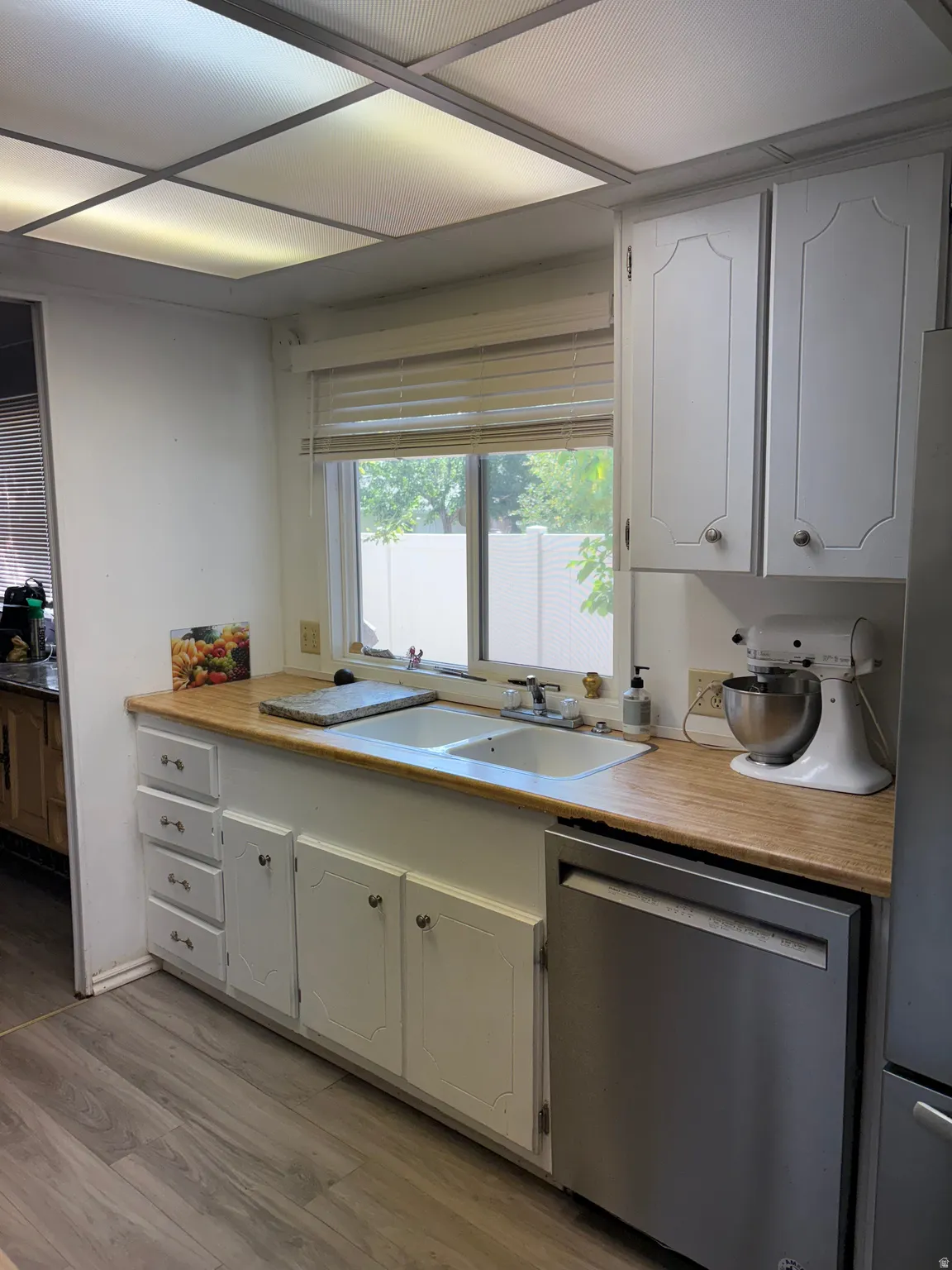 Kitchen with light wood finished floors, stainless steel appliances, and white cabinets