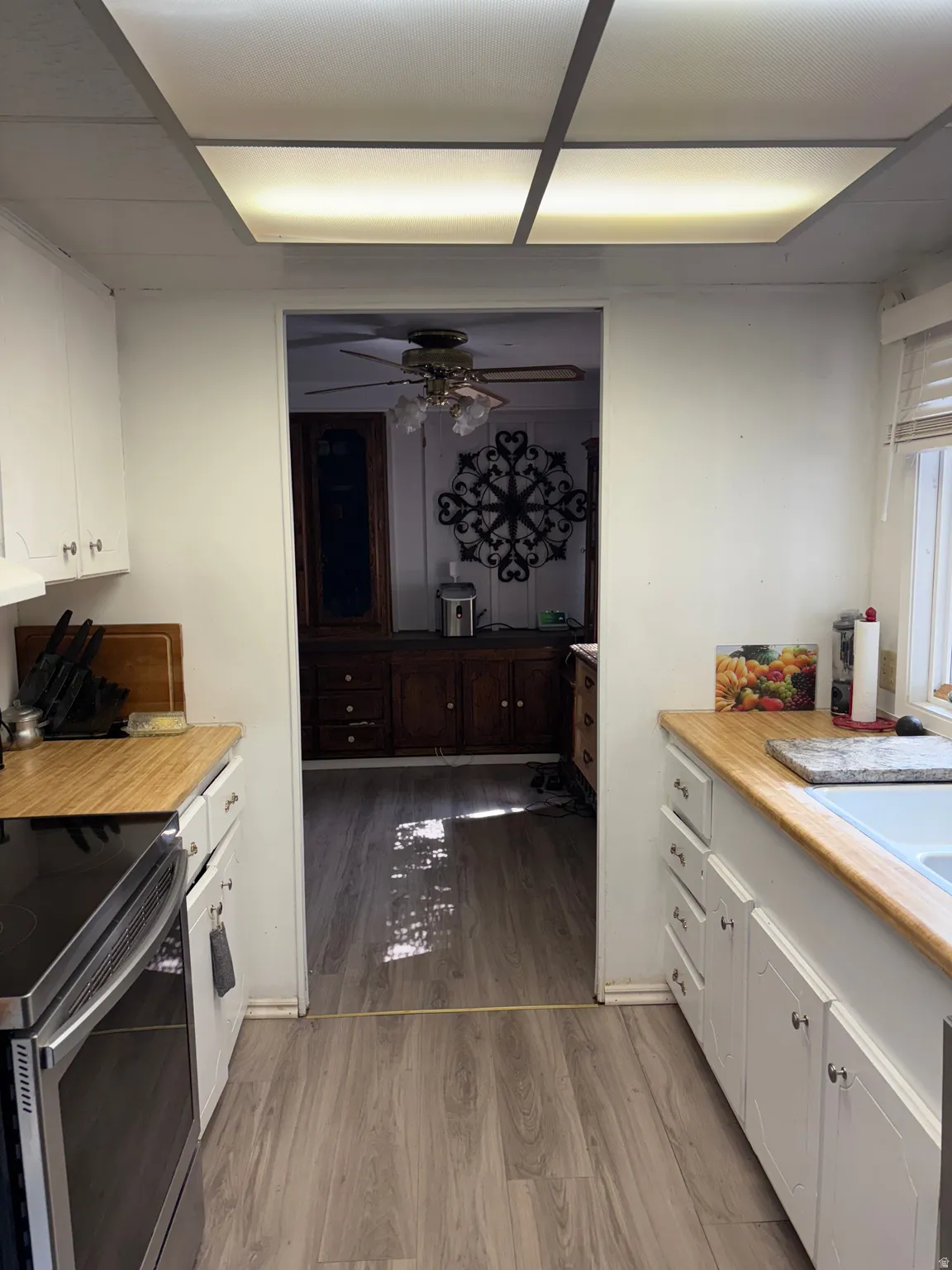Kitchen with white cabinetry, electric stove, light wood finished floors, ceiling fan, and wooden counters