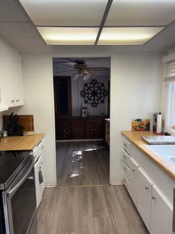 Kitchen with white cabinetry, electric stove, light wood finished floors, ceiling fan, and wooden counters