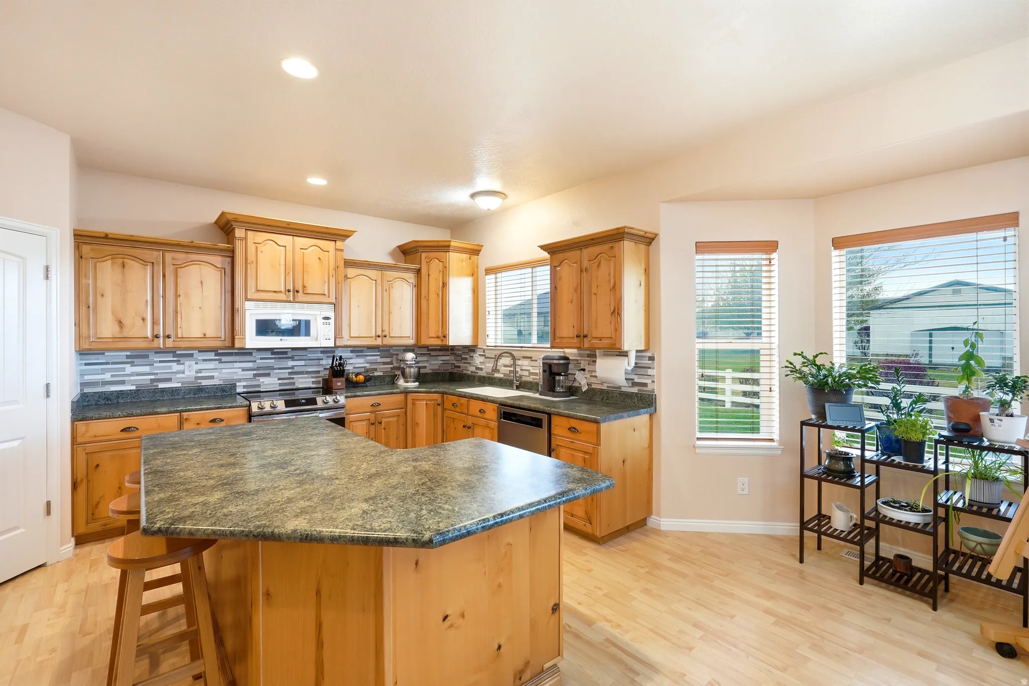 Kitchen featuring light wood-style floors, tasteful backsplash, a breakfast bar area, stainless steel appliances, and recessed lighting