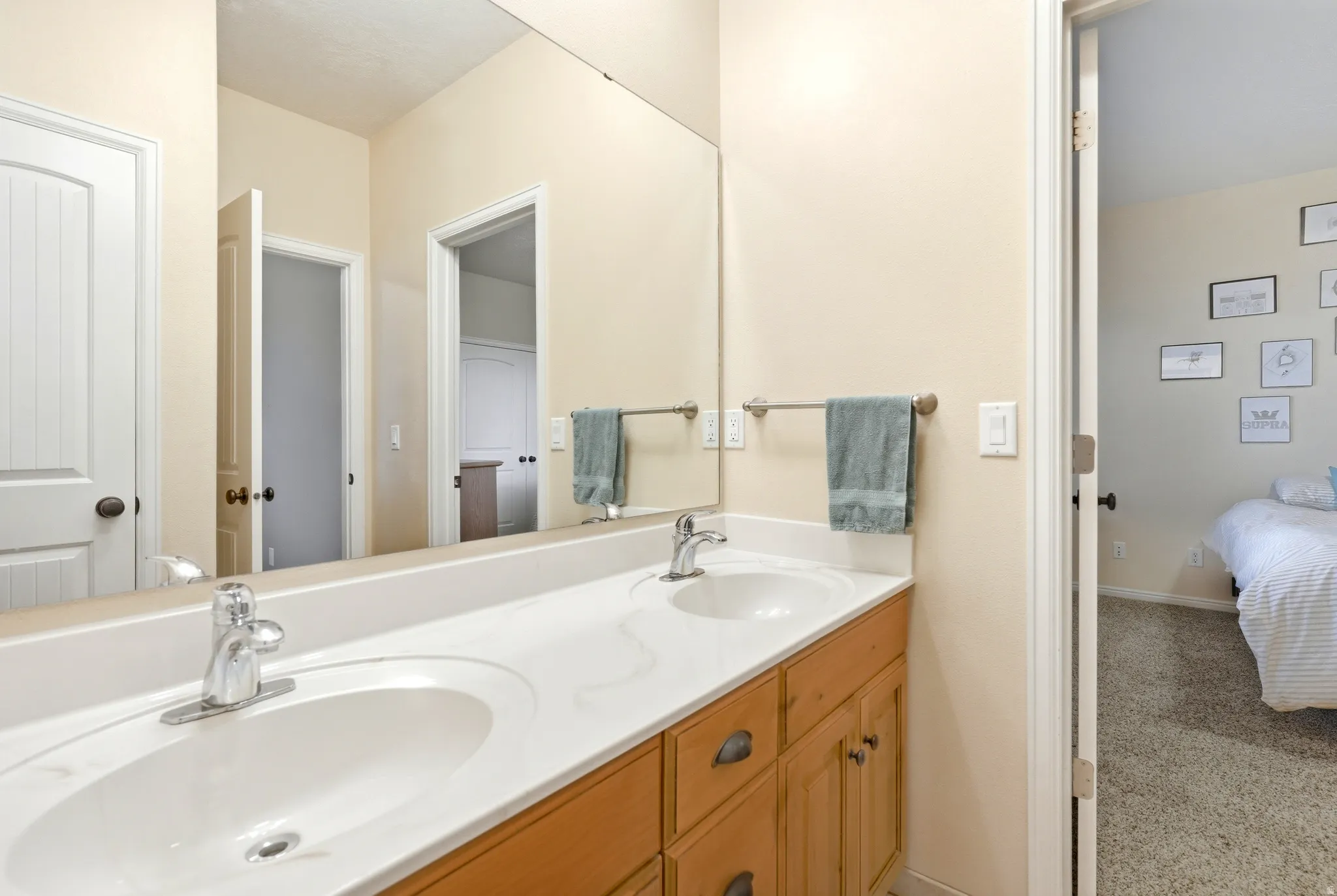 Ensuite bathroom featuring double vanity and light carpet
