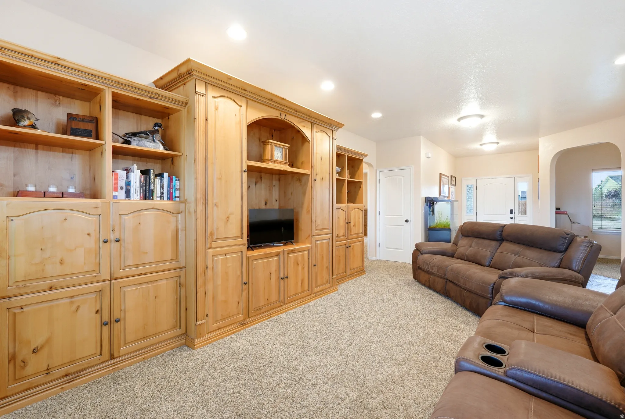 Living area featuring arched walkways, carpet floors, and recessed lighting
